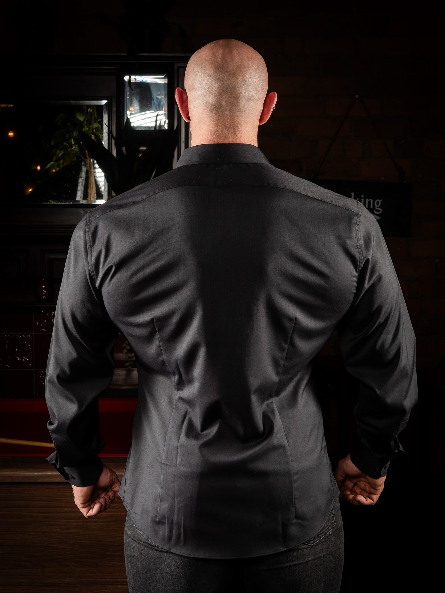 Person wearing a black muscle fit shirt with taper from shoulders to waist